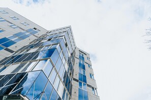 Een hoog gebouw met een moderne glazen gevel en een herkenbaar 'Hotel'-bord.