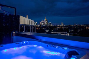 Un tetto con idromassaggio e lo skyline della città sullo sfondo.