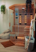Una sauna con porte in vetro, panche di legno e una pianta sospesa.