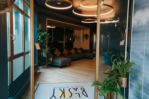 Um interior moderno com área de estar, entrada por porta de vidro e um aviso com texto.