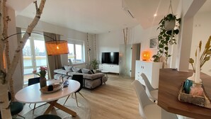 Una sala moderna con sofá, televisión y comedor con sillas y una mesa.