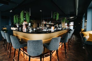 Een bar met een gebogen toonbank, barstoelen, hangplanten en diverse barbenodigdheden.