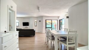 Amplia sala de estar con sofá, televisión y mesa de comedor con sillas.