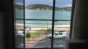 A view from a window overlooking a beach with a vehicle parked in the foreground. - Apartment on the ocean and the beach. . (santa marta de ortigueira)