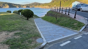 A paved pathway leading to a beach with a guardrail and street lamps. - Apartment on the ocean and the beach. . (santa marta de ortigueira)