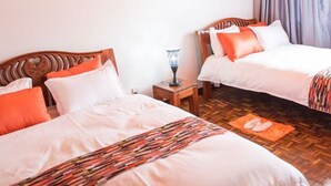 A room with two beds, wooden headboards, a wall-mounted light fixture, a hanging light, and a framed picture.