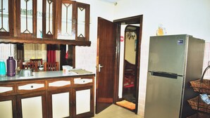 A kitchen with wooden cabinets, a stainless steel refrigerator, and a tiled floor.