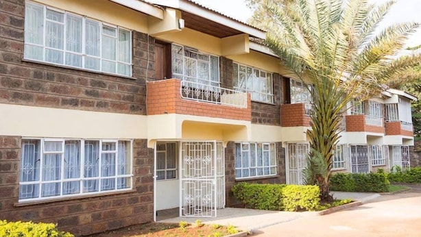 A multi-story residential building with balconies, large windows, and a well-maintained garden.