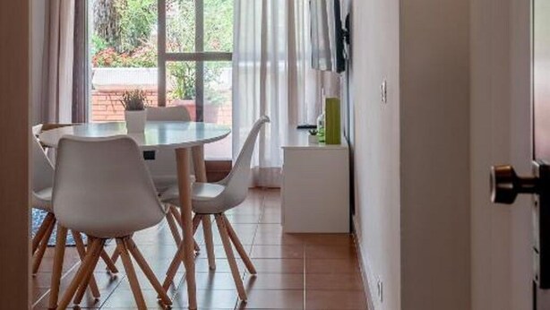 A dining area with a round table and chairs, a window with curtains, and a wall-mounted air conditioner. - Il Parco Apartments - Apartment with Terrace (Marina di Massa)