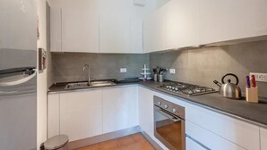 A compact kitchen with white cabinets, a stainless steel sink, a gas stove, and a built-in oven. - Il Parco Apartments - Apartment with Terrace (Marina di Massa)