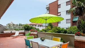 A patio with a table and chairs, a green umbrella, and a brick wall. - Il Parco Apartments - Apartment with Terrace (Marina di Massa)