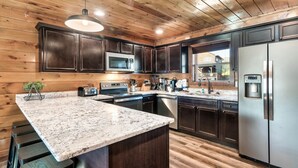 Una cocina moderna con armarios de madera oscura, electrodomésticos de acero inoxidable y encimera de granito.