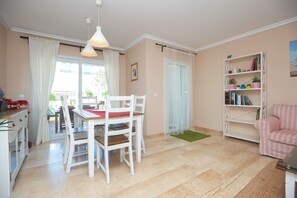Un coin repas avec une table et des chaises, une bibliothèque et une fenêtre avec des rideaux.