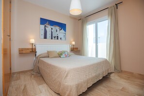 Une chambre à coucher avec un lit, un tableau, une fenêtre et une porte.