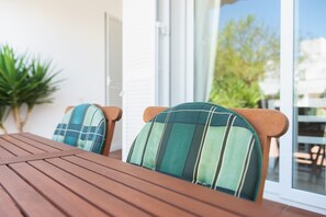 A wooden table with two chairs, each with a green and blue checkered cushion.