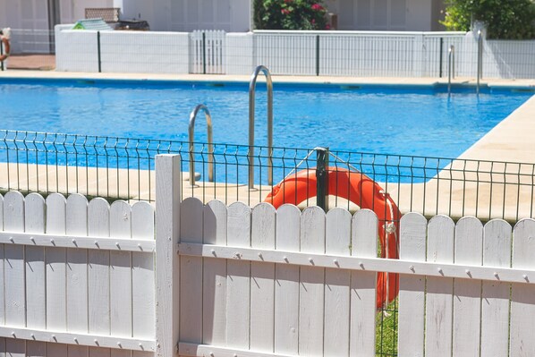 A swimming pool with a white picket fence and a lifebuoy.