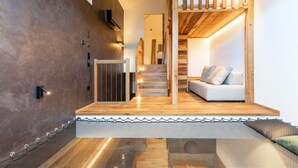 A modern interior with a staircase, a sofa, and a wall-mounted light fixture. - Apartment "Innerbachlerhof Laugen" with Wi-Fi, Air Conditioning, Garden & Pool (Postal)