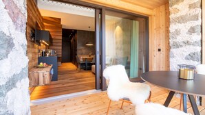 A wooden interior with a dining area, a white fluffy chair, and a table with a candle. - Apartment "Innerbachlerhof Laugen" with Wi-Fi, Air Conditioning, Garden & Pool (Postal)