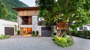 A two-story building with a stone facade, a wooden balcony, and a gravel driveway. - Apartment "Innerbachlerhof Laugen" with Wi-Fi, Air Conditioning, Garden & Pool (Postal)