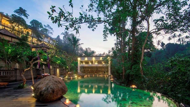 An infinity pool with a wooden deck, surrounded by lush greenery and a building with multiple floors. - Private room in a valley of Ubud, feel the tranquility of Ubud by the river (Ubud)