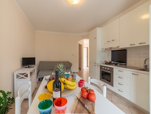 A modern kitchen with white cabinets, a built-in oven, and a dining area with a table set for two. - Bright Holiday Home "Asia" Near the Beach in Otranto (Otranto)