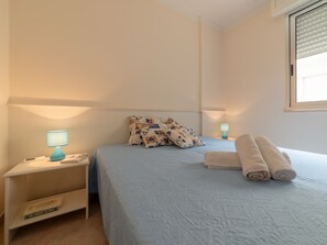 A bedroom with a bed, two bedside tables with lamps, a window, and a wall-mounted shelf. - Bright Holiday Home "Asia" Near the Beach in Otranto (Otranto)