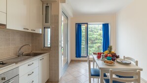 Una cocina moderna con armarios blancos, un lavamanos de acero inoxidable y una zona de comedor con una mesa preparada para dos personas.