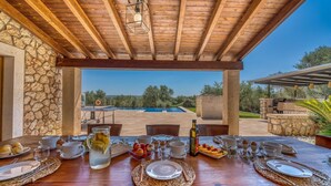 A wooden table set for breakfast with a view of a swimming pool and outdoor seating.