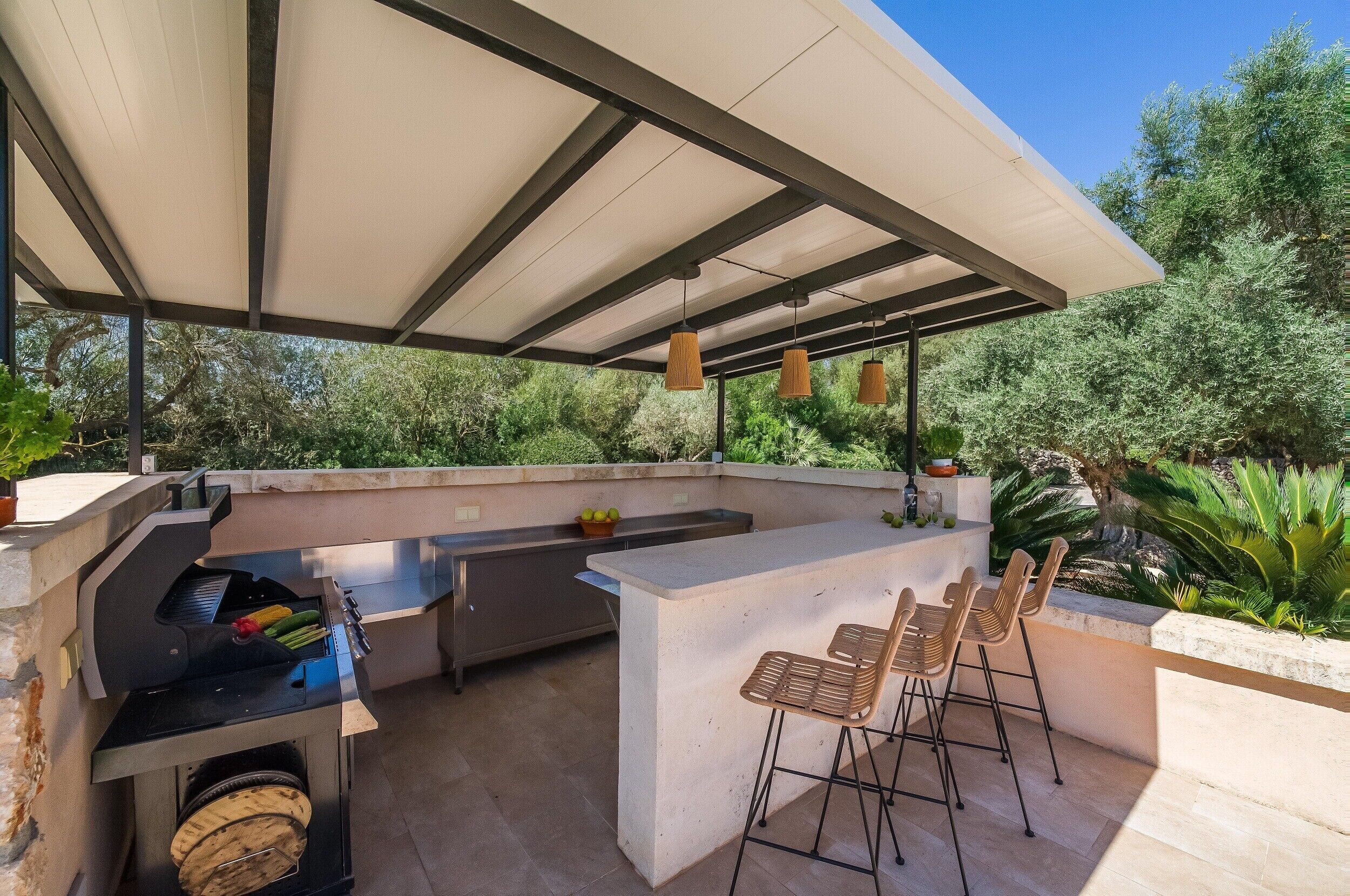An outdoor kitchen with a grill, bar area, and seating.