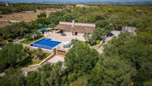 A villa with a swimming pool, surrounded by dense trees and a clear view of distant mountains.