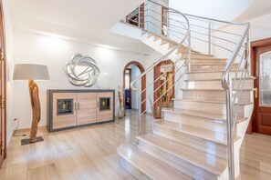 A modern interior with a spiral staircase, a wooden cabinet, and a lamp.
