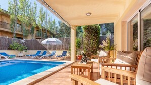 Un espace aménagé au bord de la piscine, comprenant des chaises longues, une table et un coin salon abrité.