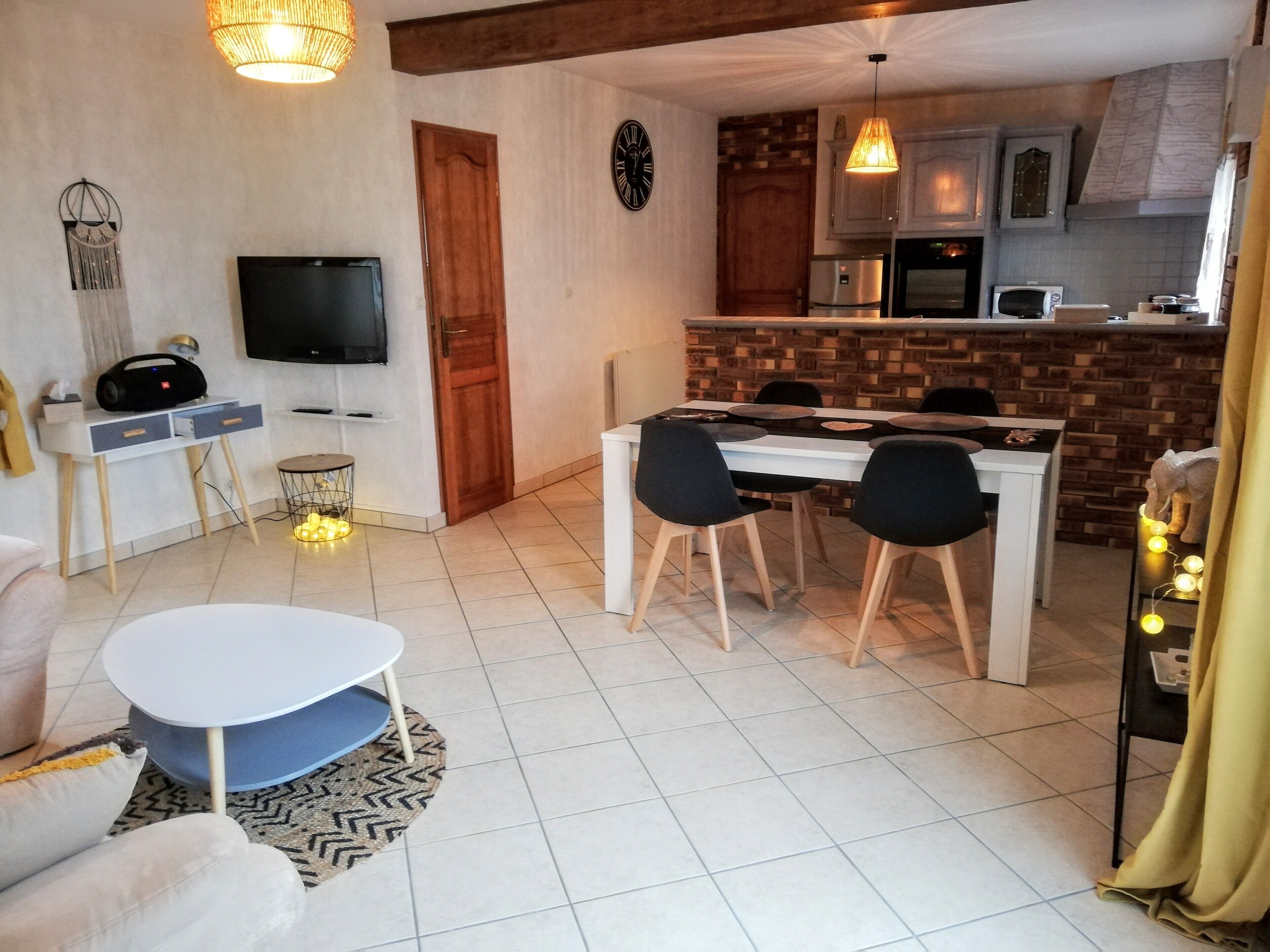 Een moderne woonkamer met een televisie, bank en een eetgedeelte met stoelen en een tafel.