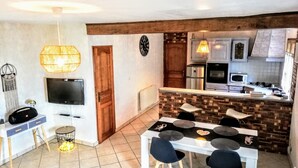 A compact living space with a dining area, kitchen, and a TV.