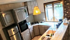 A modern kitchen with stainless steel appliances, a large island with a sink, and a hanging pendant light.