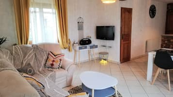 A living room with a sofa, a coffee table, a TV, and a dining area with a table and chairs.