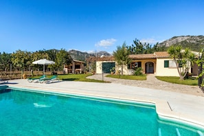 Ein Pool mit Liegestühlen, einer Terrasse und einem Blick auf die Berge.