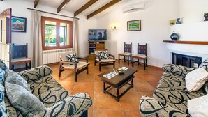 A living room with patterned sofas, a wooden coffee table, a TV, and a fireplace. - Rural villa with pool – Villa Tabo (Selva)