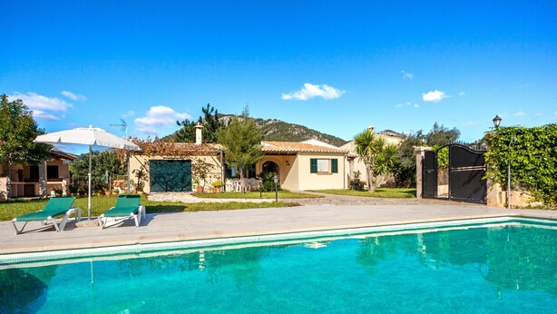 A swimming pool with lounge chairs, a small building with a tiled roof, and a mountainous backdrop. - Rural villa with pool – Villa Tabo (Selva)