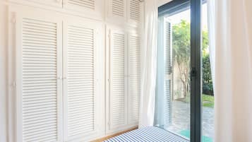 Ein Schlafzimmer mit großem Fenster, weißen Fensterläden und einer gestreiften Bettdecke.