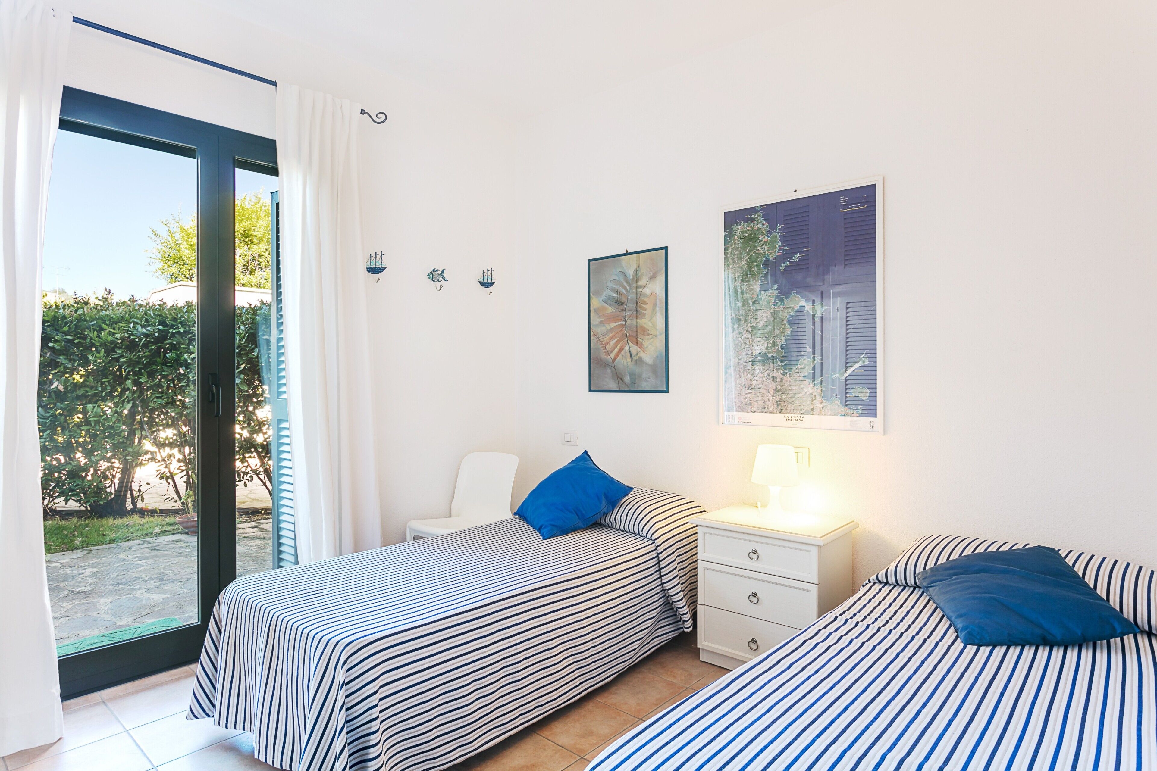 Ein Schlafzimmer mit zwei Betten, einem Nachttisch, einem Stuhl und einem Fenster mit Vorhängen.