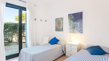 Ein Schlafzimmer mit zwei Betten, einem Nachttisch, einem Stuhl und einem Fenster mit Vorhängen.
