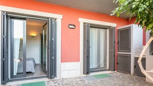 Entrada de hotel com porta de vidro deslizante que dá para um quarto com uma cama e um tapete verde.