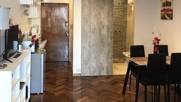 Een moderne keuken met witte kasten, een visgraat houten vloer en inbouwspots.