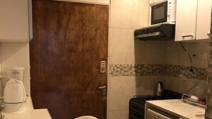 Een kleine keuken met een magnetron, fornuis en wasmachine.