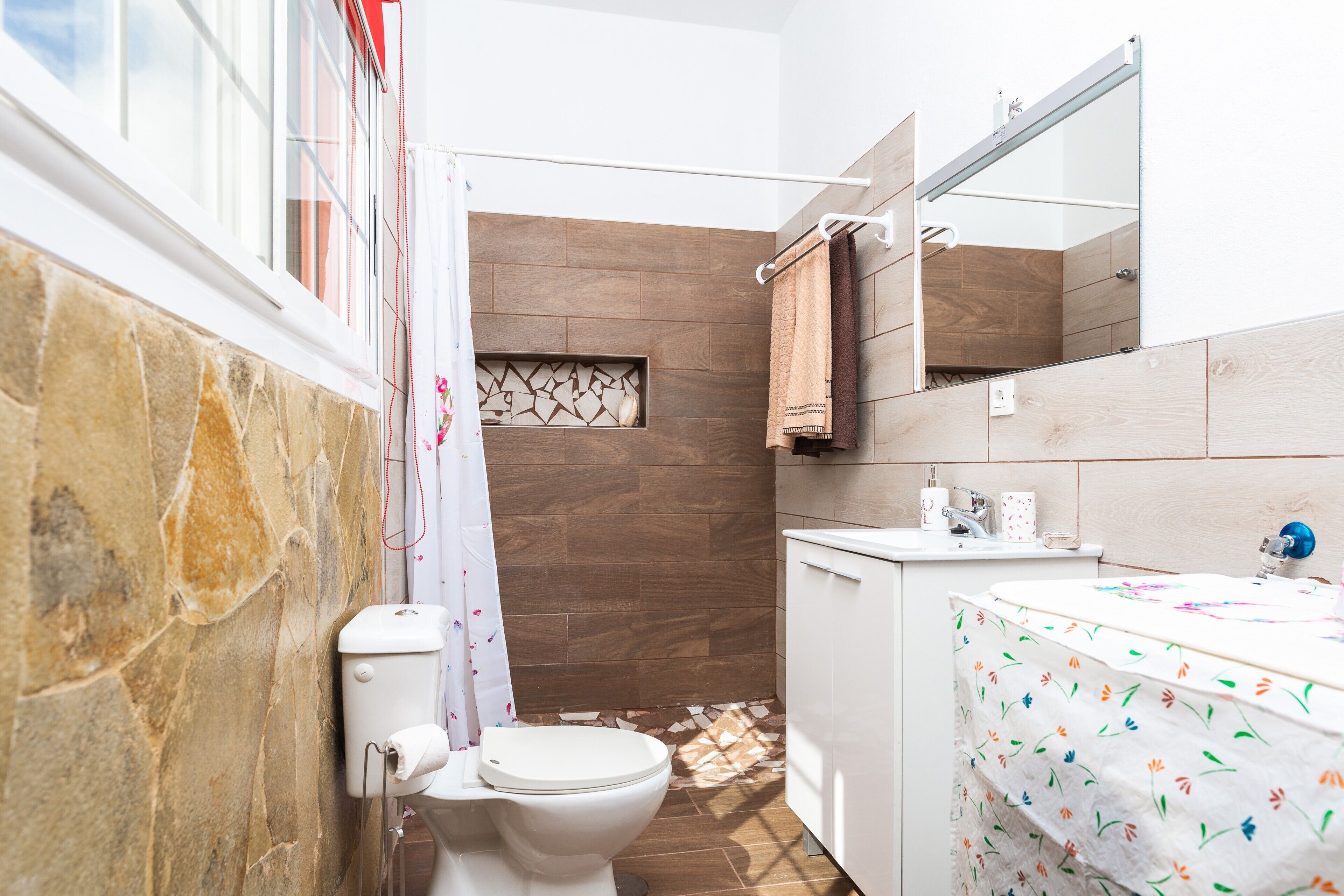A bathroom with a toilet, shower, and sink.