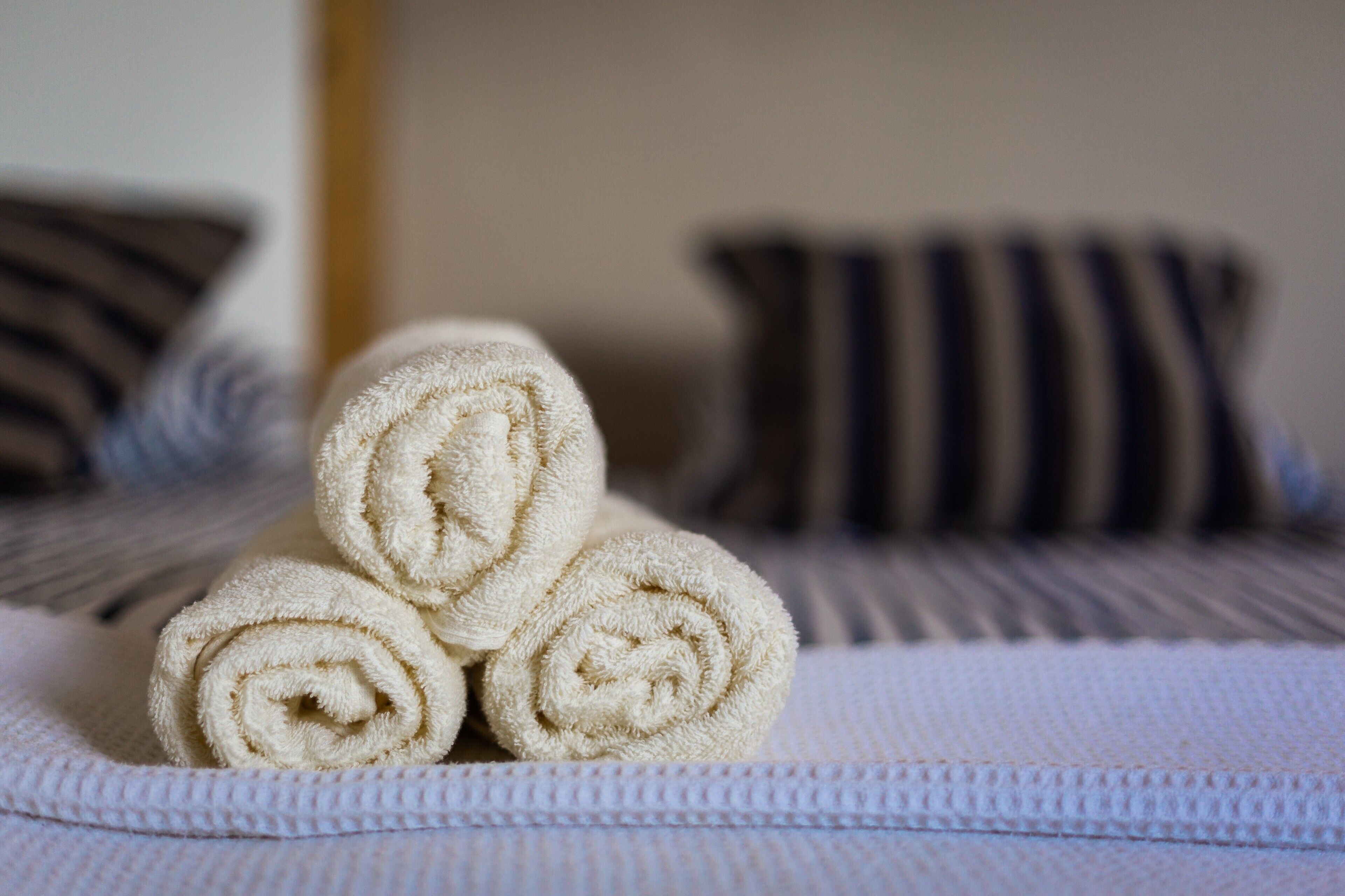 Una cama con toallas blancas enrolladas y almohadas a rayas.