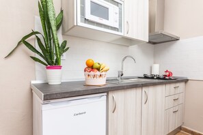 A kitchen with a microwave, sink, and a dishwashing unit.