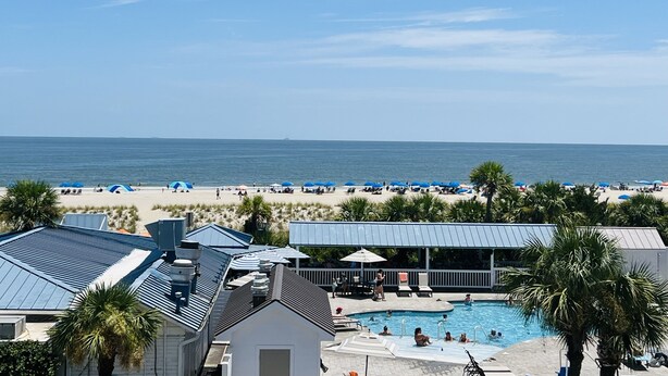 Een resort met een zwembad, strandparasols en uitzicht op de oceaan.
