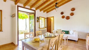 A dining area with a wooden table and chairs, a white sofa, and a view of the outdoors.